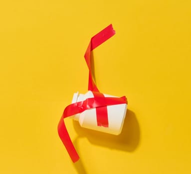 A small white bottle is tightly wrapped and secured with bright red electrical tape against a yellow background