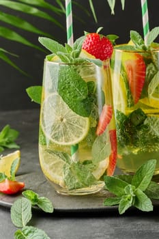 A refreshing drink in a glass with lemon slices, strawberries, fresh mint leaves, and sparkling water