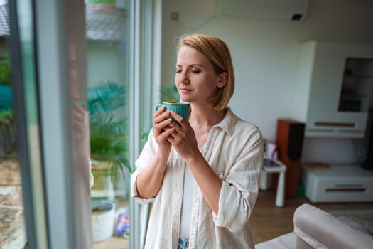 Woman enjoys a warm drink while gazing out the window