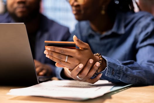 African american young couple entering credentials to renew a subscription, managing streaming services on their laptop. Couple transferring money on the browser, updating the digits.