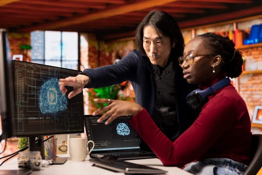 Man in AI startup office CTO position overseeing software technician implementing machine learning. Artificial intelligence tech venture experienced supervisor helps staff member to fix code bugs