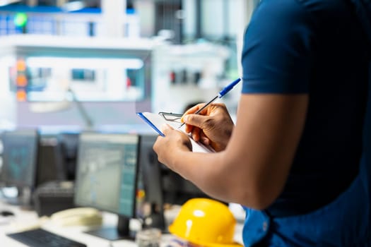 Solar panel manufacturing plant researcher taking notes on files, developing new solar energy systems prototypes. Engineer inspecting new photovoltaics materials, writing down info.