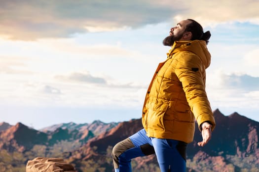 Pleased active explorer gazes at the endless sky and towering peaks, reflecting on extreme hiking activity and conquering fears. Enjoys breathtaking mountain view, nature lover.