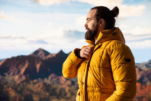Adventure seeker gazes at the valley and mountain peaks ahead, feeling the freedom of the open wilderness. Young explorer fully equipped enjoying high altitude outdoor exploration.