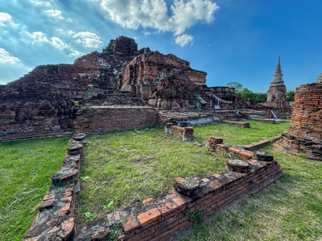 Stunning sunlit view of Wat Maha That traditional Buddhist temples, admiring ancient brick architecture at the famous Thailand landmark. Spiritual and cultural tourist attraction.