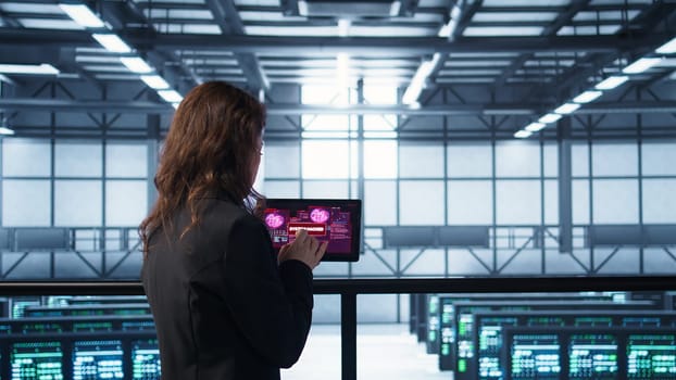 Data center engineers struggling to contain virus infestation, working on securing servers. Team of server farm employees detecting hacker attacks on tablet, fighting back, camera B