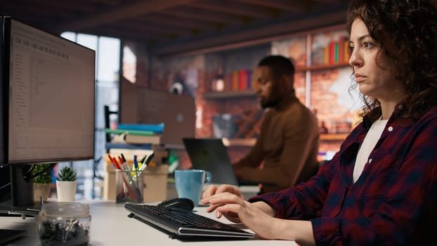 Company personnel sitting at desks in startup office, imputing data on computers. Man entering venture agency room holding laptop next to staff members in solving tasks during job shift, camera A