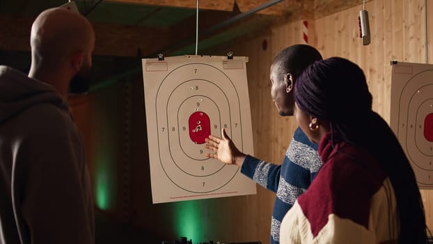 Shooting gallery safety officer explaining bullseye scoring system and reading rules. Firing range expert teaching bullseye points system and discussing industry regulations, camera A