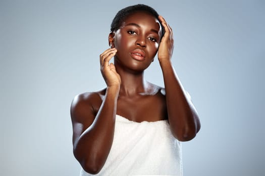 A model with short, curly hair poses against a soft background, showcasing healthy skin and effortless beauty.