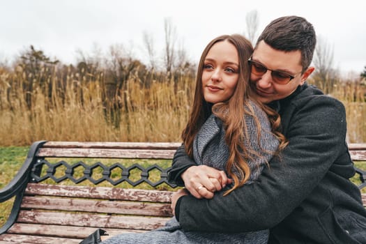 In a peaceful park setting, a couple is seated together on a bench, sharing an intimate moment.