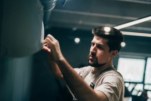 A focused man works diligently to install equipment in a contemporary fitness studio. Bright lights illuminate the space as he adjusts settings in a quiet early morning atmosphere.