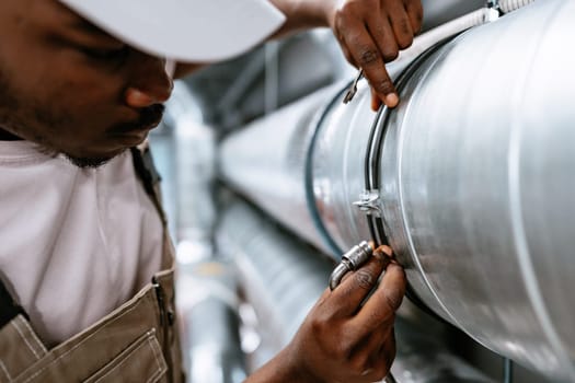 A technician focuses on securing a metal pipe in an industrial environment, showcasing attention to detail and craftsmanship during the workday.