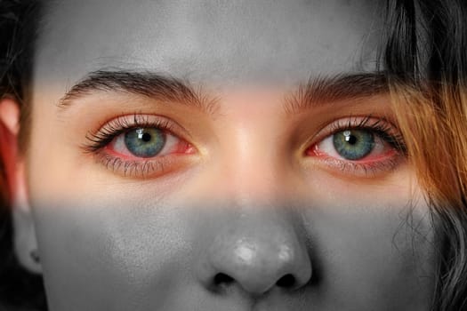 A close-up of a person's face reveals bright blue eyes that stand out against a monochrome background. The play of light creates a dramatic effect on their features.