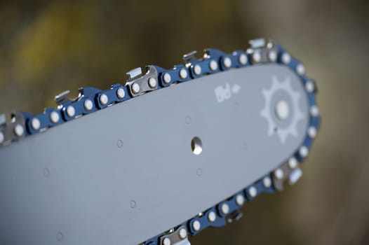 A close-up shot highlights the chain of a chainsaw, showcasing its sharp, metallic teeth and detailed structure.