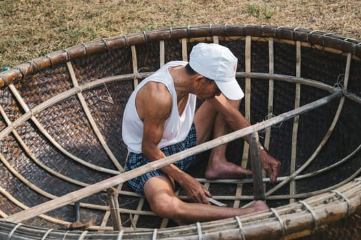 Vietnamese male fisherman craftsman makes a traditional round Vietnamese bamboo basket boat Thung Chai. Tam Thanh, Quang Nam province, Vietnam - April 10, 2025