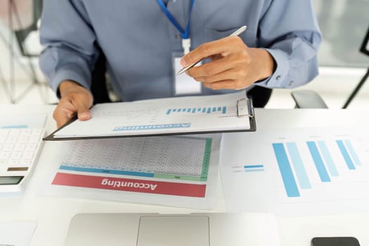 A professional examines financial reports and documents, emphasizing accuracy in financial analysis in a modern office setting.