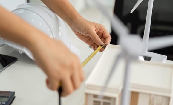 A professional carefully measuring a model building, focusing on precision and sustainability in architectural design.