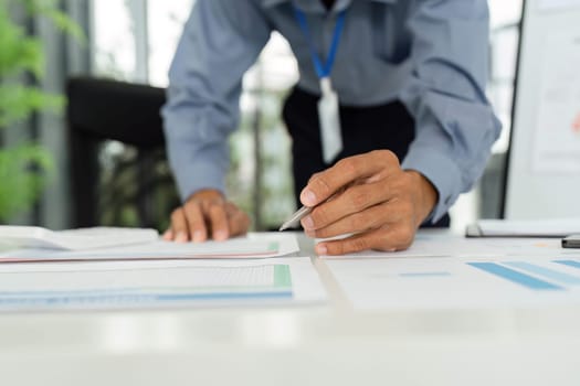 A businessman examines financial reports closely, demonstrating attention to detail and strategic planning in a modern office.