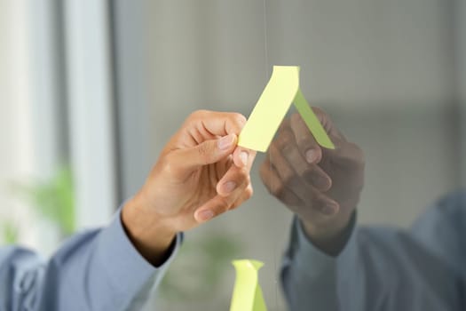 A focused professional engages in brainstorming by holding sticky notes, reflecting collaborative work in a modern office environment.