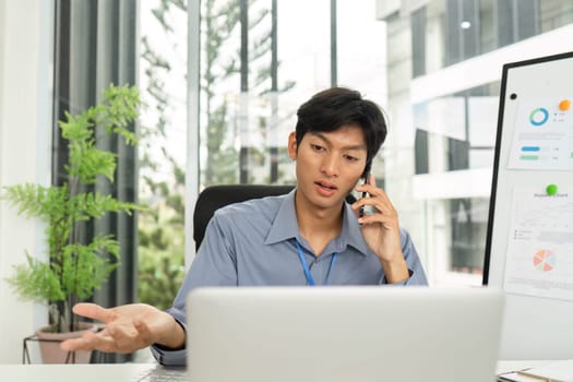 A young man animatedly discussing financial strategies on a call while reviewing data in a contemporary office environment.