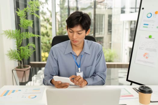 A young professional uses a smartphone while reviewing business documents, highlighting effective data management in a digital workspace.