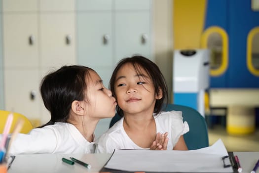 Two young girls share a sweet moment in class, highlighting friendship and emotional connection while learning together.