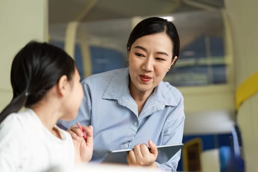 A teacher interacts with a young girl, fostering a positive learning environment in a classroom setting.