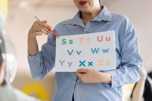 An educator uses a colorful chart to teach young children the alphabet in a lively classroom setting, promoting early literacy.