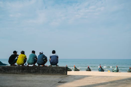 Back of Vietnamese male fishermen relaxing on beach by the sea in Fishing Village n Vietnam. Tam Thanh, Quang Nam province, Vietnam - April 10, 2025