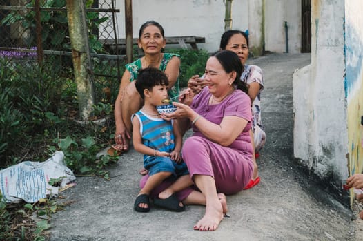 Vietnamese family on street in a village in Vietnam. Asian grandmothers with a boy grandson walking. Tam Thanh, Quang Nam province, Vietnam - April 10, 2025
