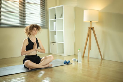 Peaceful young woman practices meditation in a bright home.