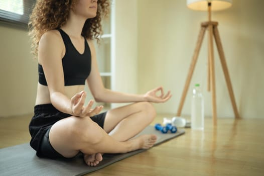 Peaceful young woman practices meditation in a bright home.