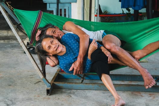 Happy couple of elderly Vietnamese in love hugging on a hammock. Asian old family in the village in Vietnam. Tam Thanh, Quang Nam province, Vietnam - April 10, 2025