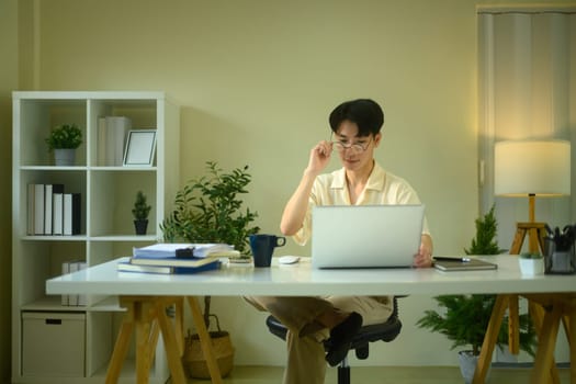 Confident man wearing glasses working on laptop in a home office.