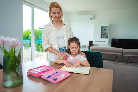 A mother helps her daughter with schoolwork at home.