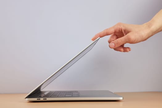 female hand open or close laptop on beige table, side view