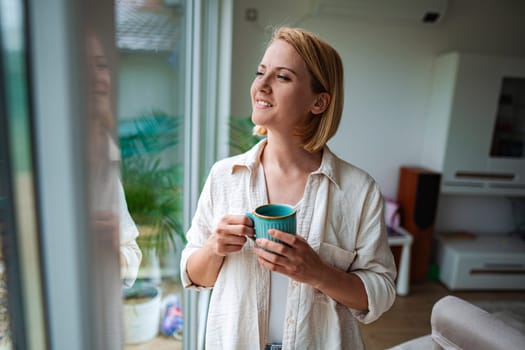 Woman savors a peaceful moment with tea by the window