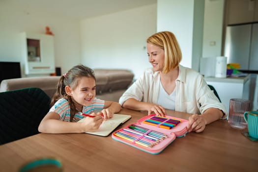 Mother and daughter enjoy coloring together at the table.