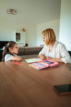 A woman shares artistic activities with a young girl.