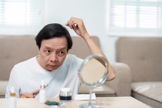An elderly man carefully styles his hair while looking in the mirror, highlighting the importance of grooming and self-care in later years.