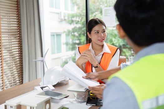 A female engineer engages with her colleagues to discuss sustainable engineering solutions, emphasizing teamwork and innovation in green tech projects.