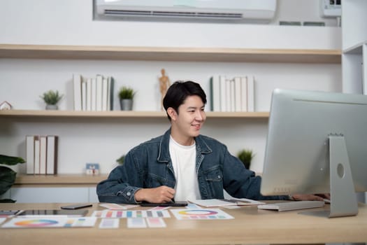 A young designer focused on his computer screen in a modern workspace, showcasing a productive design environment.