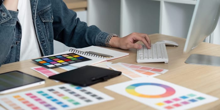 A professional engages in color coordination, using a keyboard and various swatches in a bright and organized workspace.