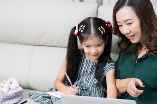A mother helps her daughter navigate online learning, emphasizing the importance of technology in education as they prepare for school.
