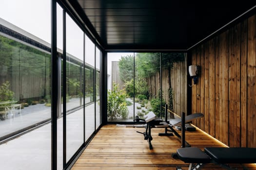 The gym features an abundance of windows that allow natural light to flood the space, complemented by beautifully crafted wooden walls