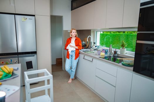 Stylish kitchen captures a woman lost in thought while cleaning.