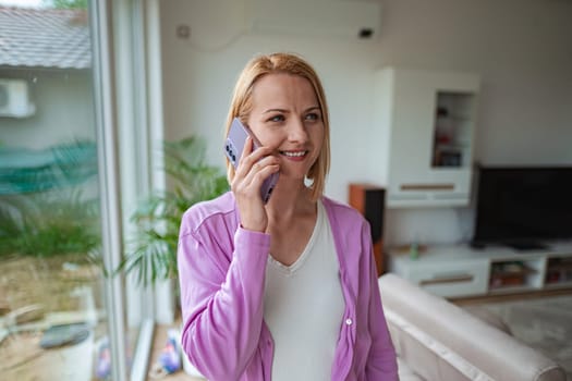 Woman happily chats on her phone while relaxing indoors.