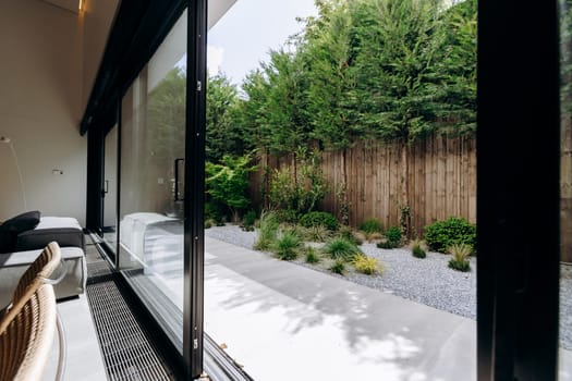 In a cozy living room, there are beautiful sliding glass doors that provide access to a lush garden outside, creating a seamless connection with nature