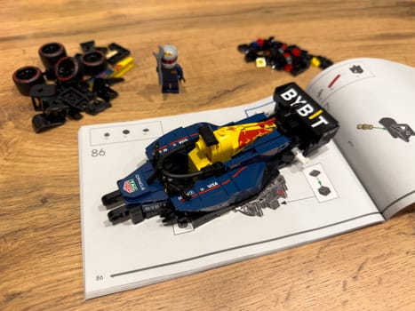 Moscow, Russia, April 26, 2025: Built LEGO Speed Champions Formula 1 car from Red Bull Racing 2024 collection placed on top of instruction manual, surrounded by scattered parts and mini figure