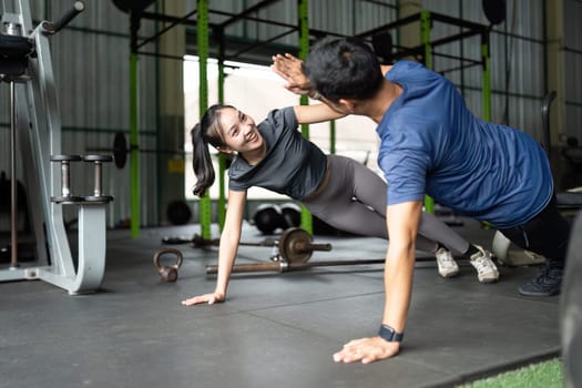 Two friends engage in a playful exercise routine, showcasing joy and camaraderie in a fitness environment.